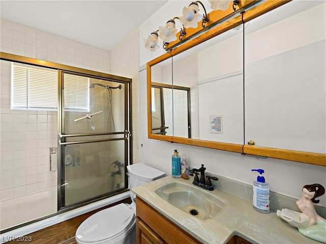 full bathroom featuring toilet, combined bath / shower with glass door, and vanity