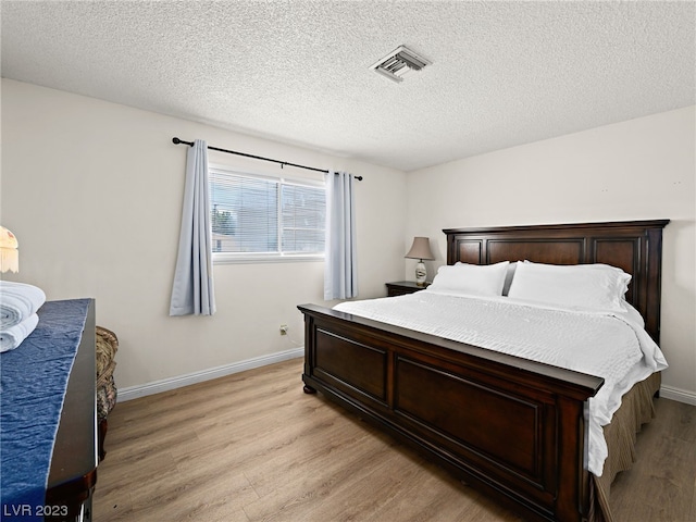 bedroom with light hardwood / wood-style floors and a textured ceiling