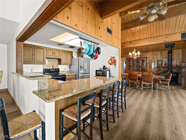 kitchen with a breakfast bar, light hardwood / wood-style floors, black appliances, and ceiling fan with notable chandelier