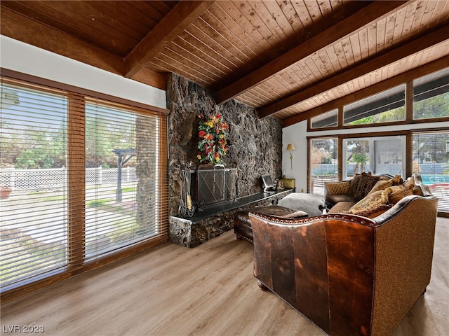 living room with wooden ceiling, lofted ceiling with beams, light hardwood / wood-style flooring, and a stone fireplace