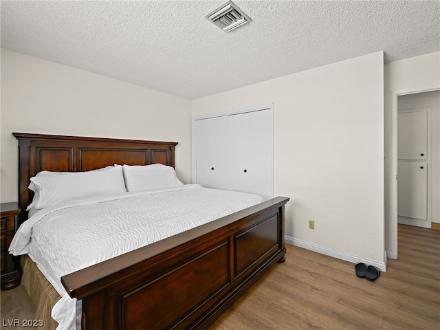 bedroom featuring light hardwood / wood-style flooring, a closet, and a textured ceiling