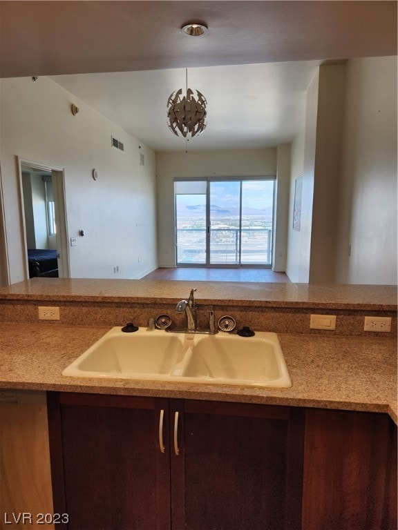 kitchen featuring an inviting chandelier, sink, and light stone counters