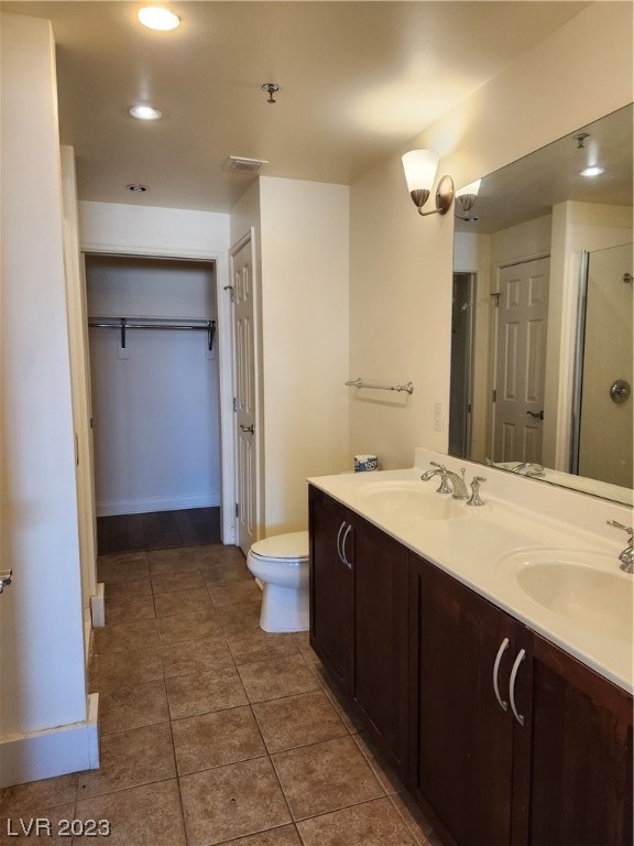 bathroom with an enclosed shower, tile flooring, double vanity, and toilet