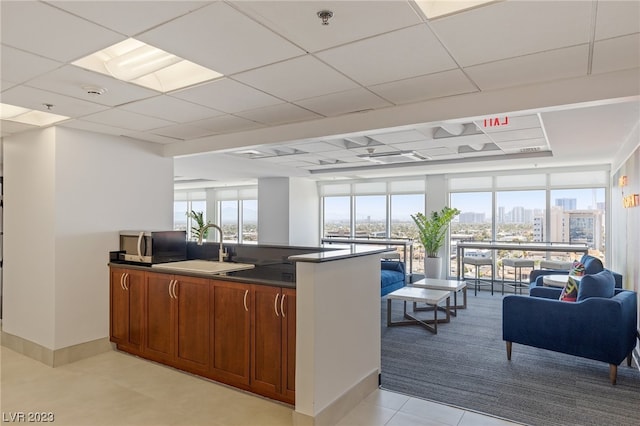 kitchen featuring light tile flooring, a healthy amount of sunlight, expansive windows, and sink