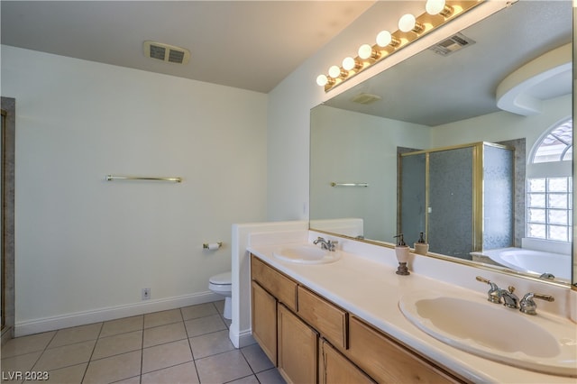 bathroom with toilet, tile flooring, dual vanity, and a bathtub