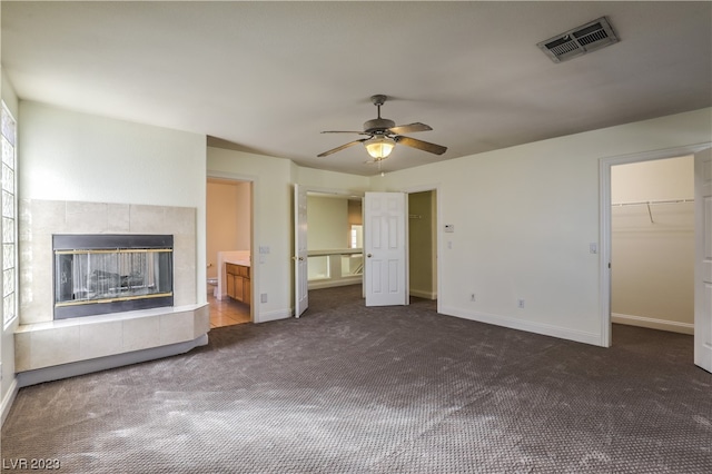 unfurnished living room featuring ceiling fan, dark colored carpet, and a fireplace