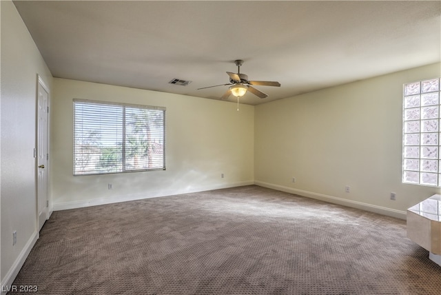 carpeted spare room featuring ceiling fan and a healthy amount of sunlight