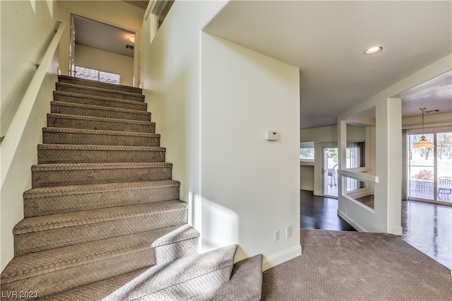 stairway featuring dark colored carpet