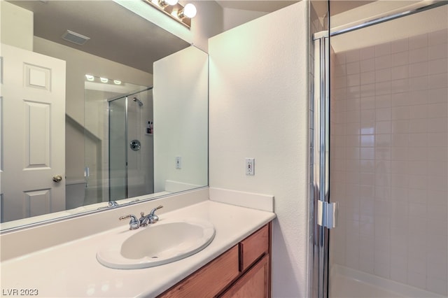 bathroom featuring a shower with door and vanity