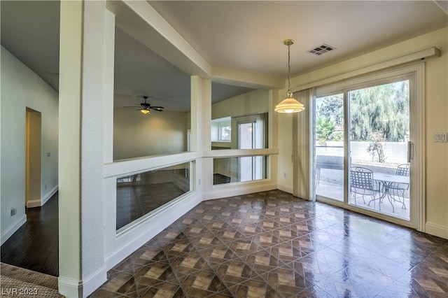 unfurnished dining area featuring dark tile floors and ceiling fan