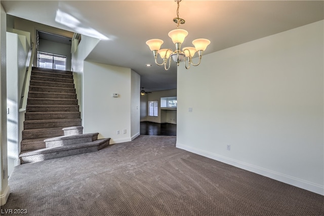 unfurnished living room with ceiling fan with notable chandelier and dark colored carpet