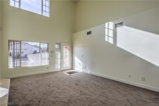 spare room featuring dark colored carpet and a towering ceiling