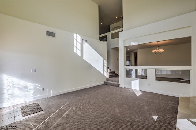 unfurnished living room with carpet floors, a towering ceiling, and an inviting chandelier