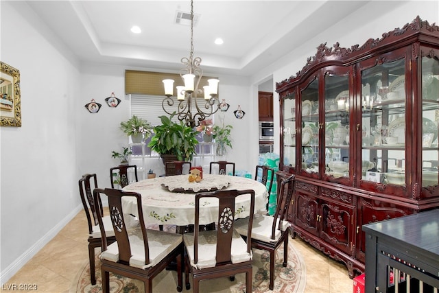 tiled dining space featuring a tray ceiling and a chandelier