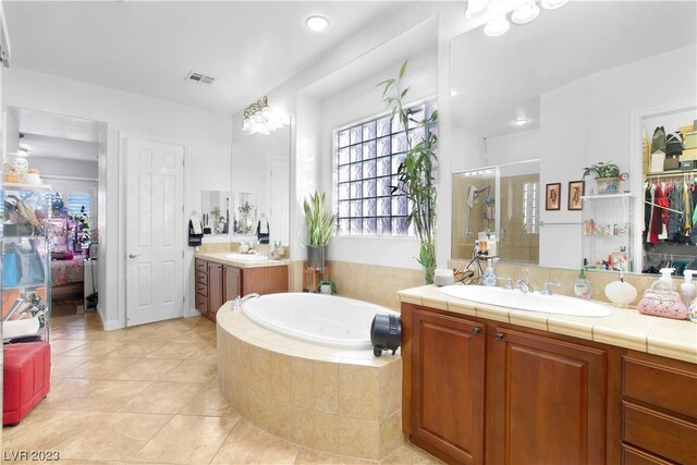 bathroom featuring tile flooring, double vanity, and tiled tub