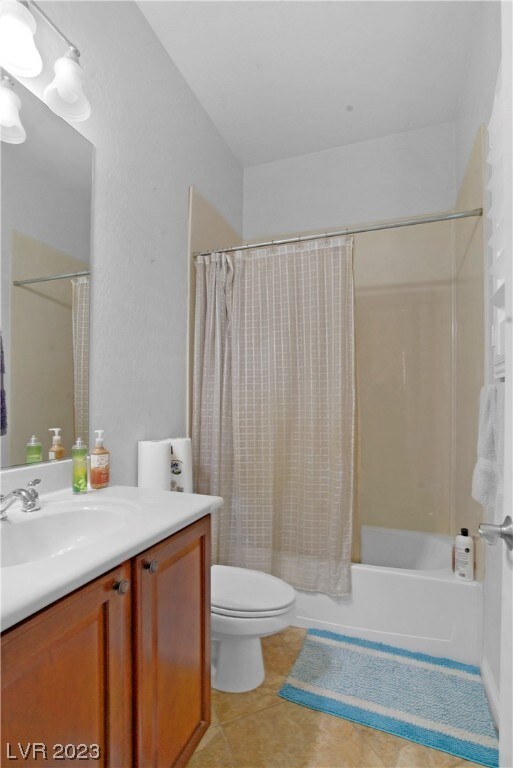 full bathroom featuring shower / bath combo with shower curtain, tile floors, toilet, and vanity