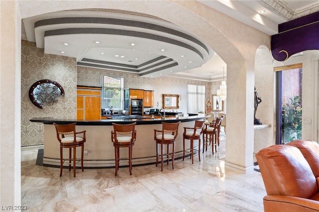 bar with sink, a raised ceiling, and black microwave