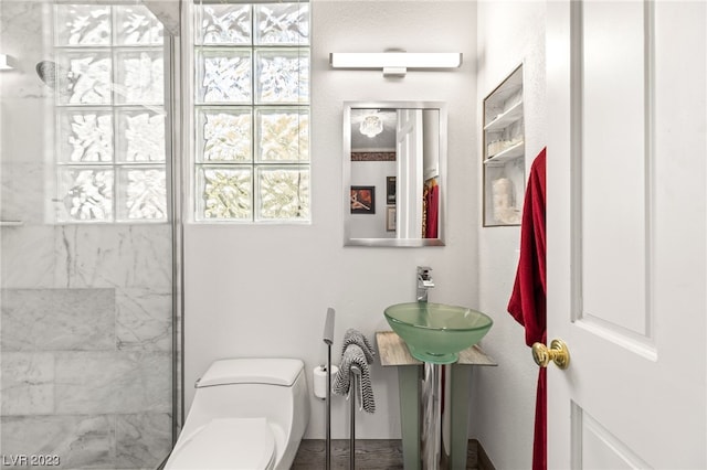 bathroom with toilet, sink, and a tile shower