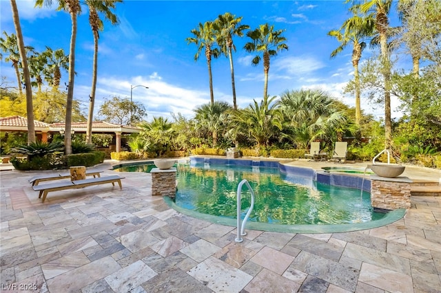 view of pool with an in ground hot tub, pool water feature, and a patio area