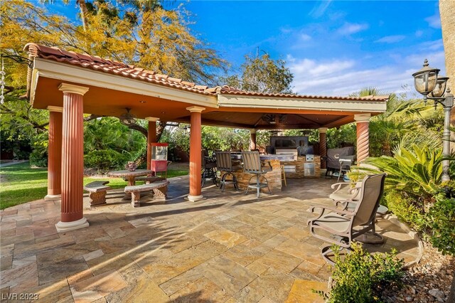 view of patio featuring exterior bar, a gazebo, an outdoor kitchen, and ceiling fan