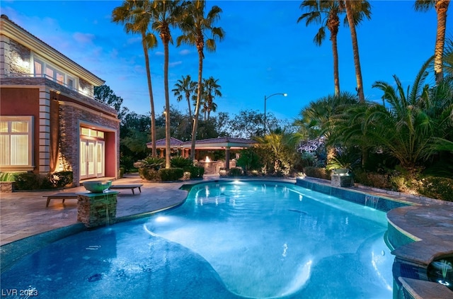 pool at dusk featuring a patio and french doors