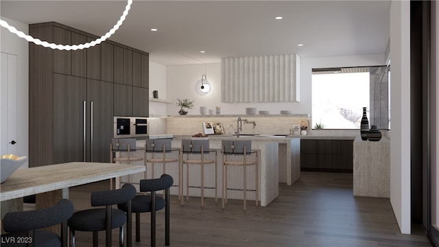 kitchen featuring sink, a center island, hanging light fixtures, a kitchen breakfast bar, and hardwood / wood-style floors