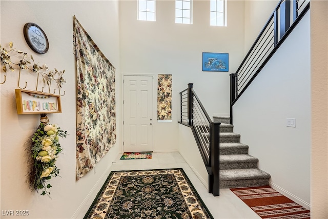 entryway with tile patterned flooring, a towering ceiling, baseboards, and stairs