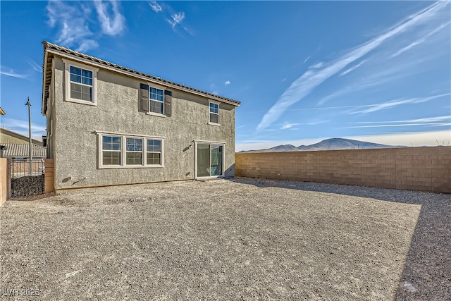 rear view of property with a fenced backyard, a mountain view, and stucco siding