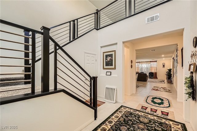 staircase featuring visible vents and a high ceiling