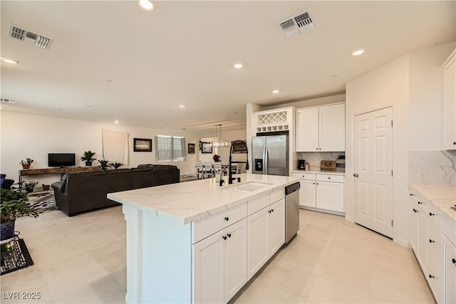 kitchen with light stone counters, visible vents, stainless steel appliances, and a sink