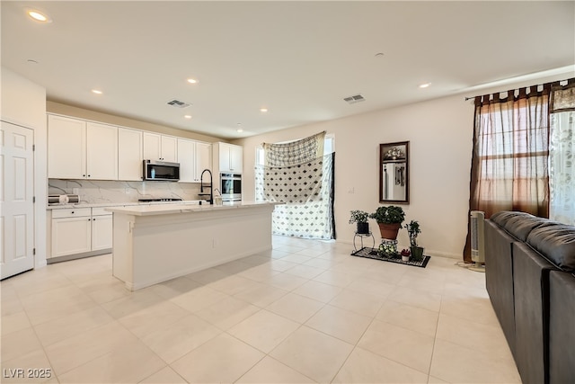 kitchen featuring light countertops, stainless steel microwave, visible vents, and white cabinets