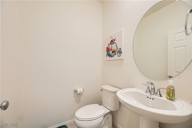 half bath featuring baseboards, a sink, and toilet