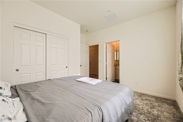 carpeted bedroom featuring a closet, ensuite bath, and baseboards