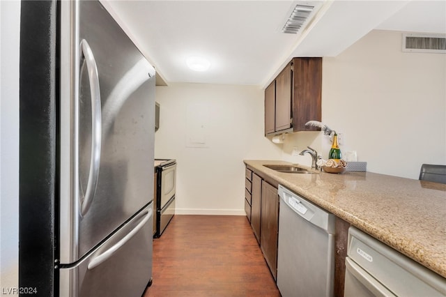 kitchen with appliances with stainless steel finishes, sink, and dark wood-type flooring