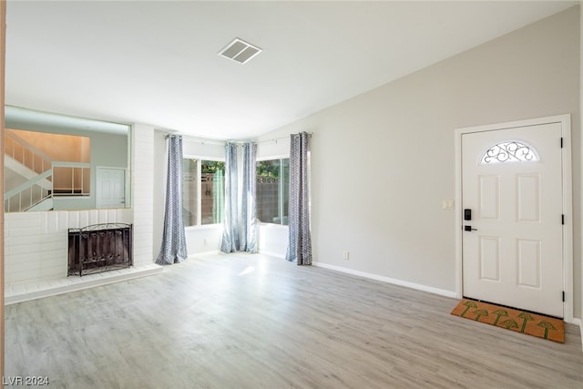 unfurnished living room featuring a brick fireplace, wood-type flooring, and a wealth of natural light