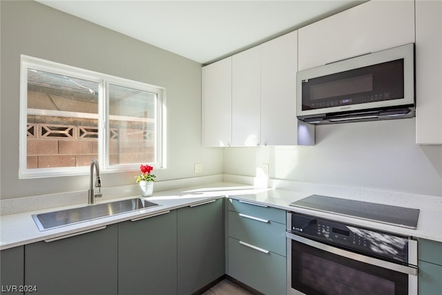 kitchen featuring appliances with stainless steel finishes, white cabinets, sink, gray cabinets, and light stone countertops