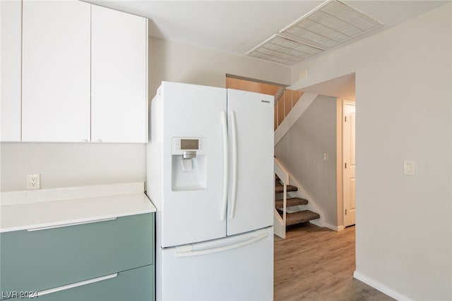 kitchen with white cabinetry, light hardwood / wood-style flooring, and white refrigerator with ice dispenser