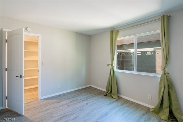 unfurnished bedroom featuring light hardwood / wood-style floors and a spacious closet