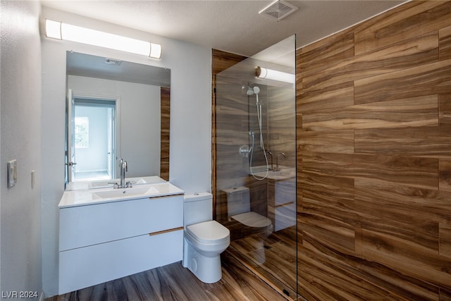 bathroom with a shower with door, toilet, vanity, and a textured ceiling