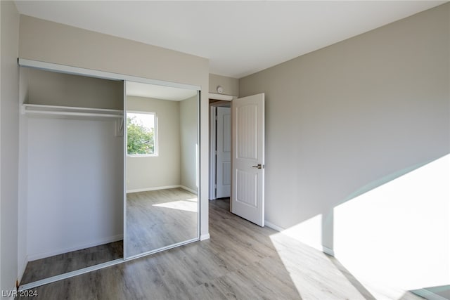 unfurnished bedroom with light hardwood / wood-style floors and a closet