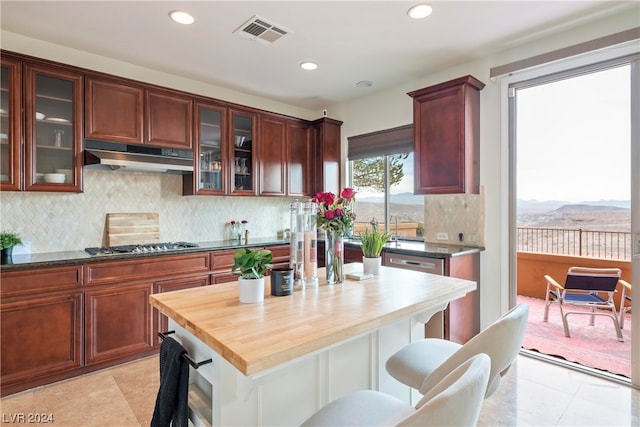 kitchen featuring a kitchen bar, stainless steel gas cooktop, decorative backsplash, butcher block countertops, and a mountain view