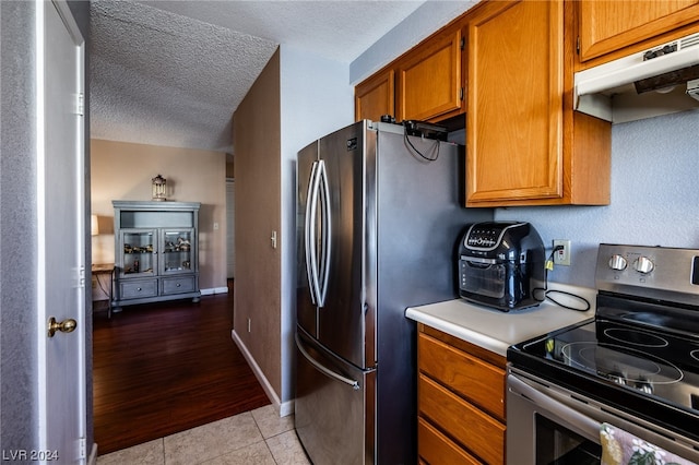 kitchen with appliances with stainless steel finishes, light tile patterned floors, and a textured ceiling