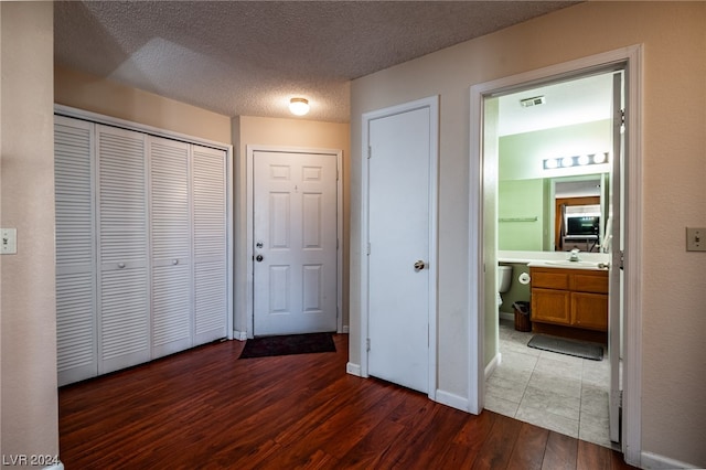 interior space with sink, dark wood-type flooring, a textured ceiling, ensuite bath, and a closet