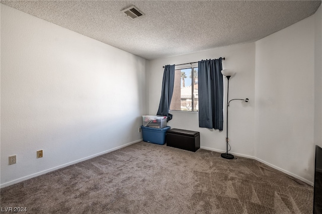 carpeted empty room with a textured ceiling