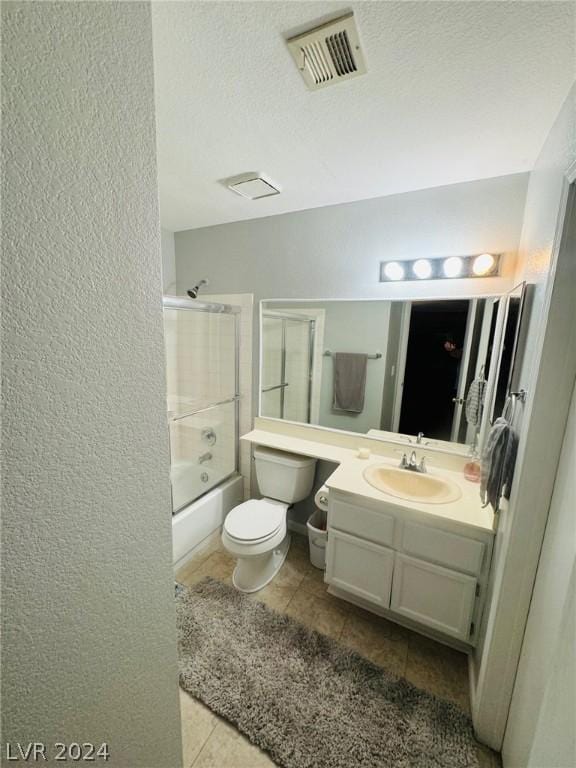 full bathroom with tile patterned floors, toilet, a textured ceiling, vanity, and enclosed tub / shower combo