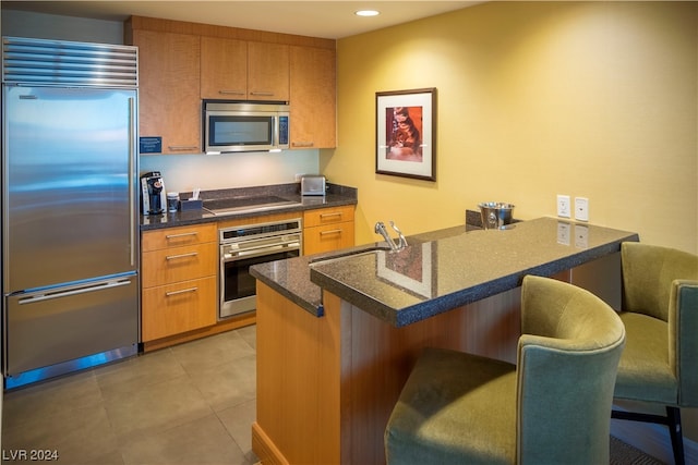 2000 N Fashion Show Dr Unit 1906, Las Vegas, NV 89109 - kitchen with kitchen peninsula, light tile floors, stainless steel appliances, and a kitchen breakfast bar