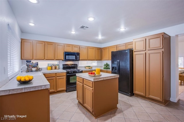 kitchen with a kitchen island, light tile patterned floors, and black appliances