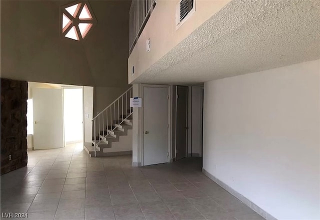 interior space with light tile floors, a high ceiling, and a textured ceiling