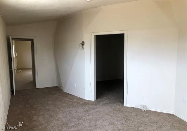 empty room featuring lofted ceiling and dark colored carpet