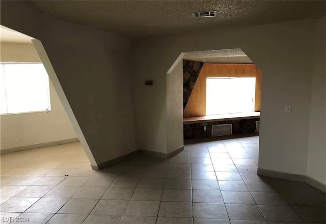 tiled empty room with a textured ceiling